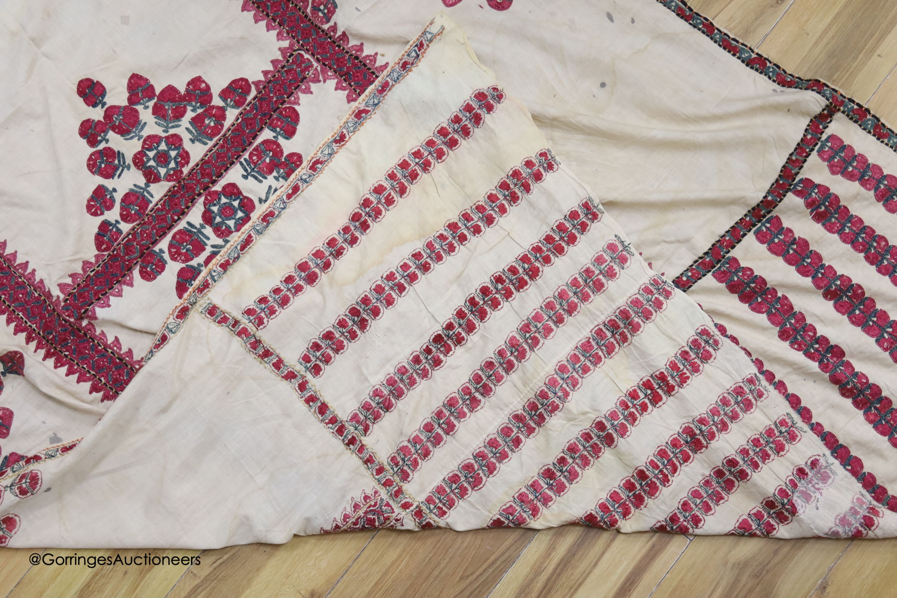 A silk embroidered Suzani, embroidered with cherry red flower heads with green stems and leaves in fine silk, width 134cm length 220cm